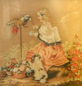 Framed needlepoint of a child feeding a parrot, with a dog and basket of flowers by her feet, 40cm x