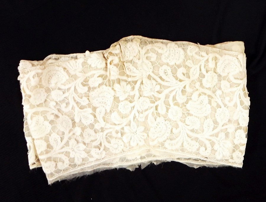 Early handmade tape lace backed onto muslin, featuring floral decoration, possibly cut from a skirt,