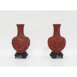 Pair of Chinese Cinnabar lacquer and blue enamel vases on wooden stands, carved with figures in