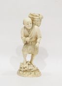 Japanese ivory okimono, late 19th century, modelled as a fisherman carrying a basket of fish over