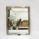 White metal rectangular silver framed table mirror with floral decoration and trestle support,