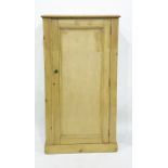 A pine single door cabinet, moulded top, above a single panelled door enclosing shelves, the whole
