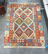 Cream ground rug with blue, green and red diamond pattern to central field on stepped border 140