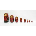 Russian Matryoshka doll painted in bright colours reserved on a red ground enclosing nine smaller