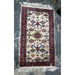 Cream ground rug, the central field decorated with assorted motifs, on stepped border, 112cm x 65cm