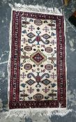 Cream ground rug, the central field decorated with assorted motifs, on stepped border, 112cm x 65cm