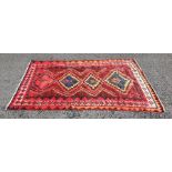 Eastern rug, red ground with four stepped lozenge shaped medallians in red, oranges, blues and pinks