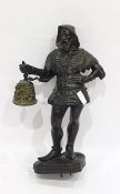 Metal figure of a man, modelled standing with his hand on his hip, holding a bell, dressed in the