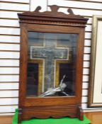 White metal crucifix mounted on a stone and marble cross, within a hinged glazed oak cabinet 65 cm x