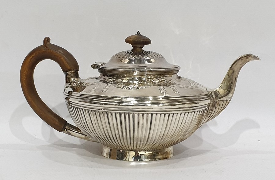 Victorian silver teapot of compressed form with repousse garland decoration and reeded body, on a