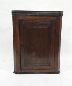 A 19th century mahogany wall-hanging corner cabinet with moulded cornice above single panel door
