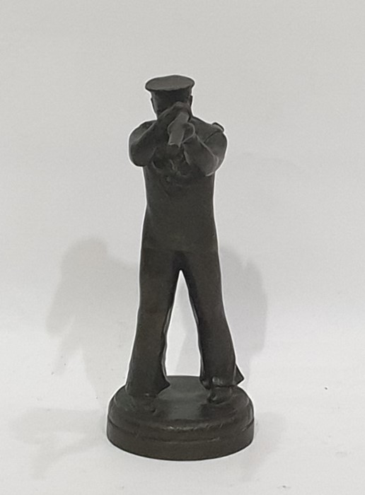 A bronze sculpture of a sailor looking through a telescope, in the Art Deco Style on a circular