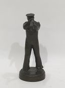 A bronze sculpture of a sailor looking through a telescope, in the Art Deco Style on a circular