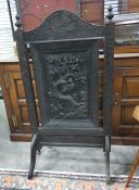 Ebonised firescreen in the Eastern taste, the arched top featuring frieze carving of birds amongst