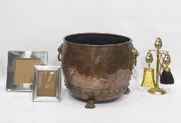 Copper cauldron on brass paw feet with lion mask and ring handles, a set of brass fireplace tools