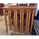 Teak coffee table with four folding coffee tables slung under, the whole on castors