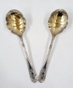 Pair of Victorian silver-gilt serving spoons, each with scalloped foliate engraved gilded bowl,