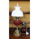 Oil lamp with cranberry glass-coloured well, on a stepped brass base, with a white opaque glass