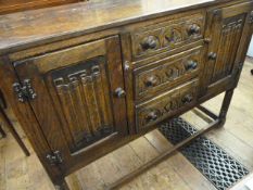 Reproduction oak side board with three drawers and two cupboards, linen fold carved on turned