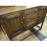 Reproduction oak side board with three drawers and two cupboards, linen fold carved on turned