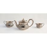 George V silver tea service comprising teapot with ivory finial, scrolling foliate embossed body,