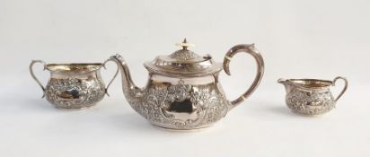 George V silver tea service comprising teapot with ivory finial, scrolling foliate embossed body,