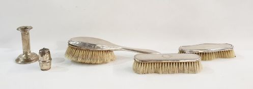 Three assorted silver-backed dressing table brushes, weighted silver candlestick and a weighted