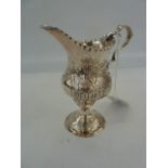 George III silver cream jug, pyraform and later repousse garden scene, on circular foot, London