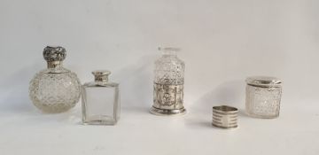 Silver-topped scent bottle with cut glass ovoid body, scrolling foliate lid, a silver engine-