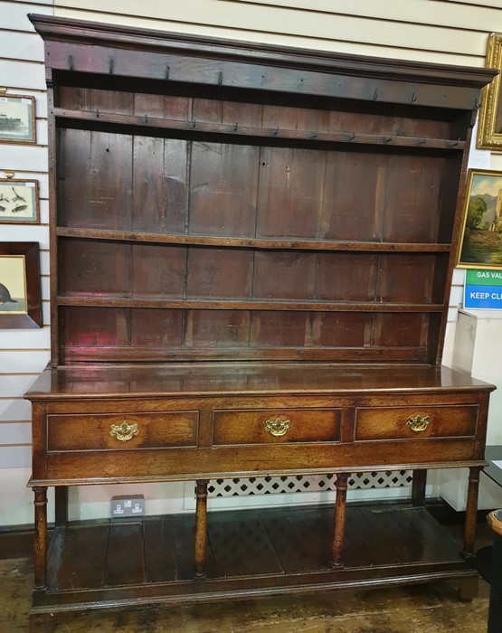 18th century oak dresser with ogee moulded pediment, three shelves with iron cup hooks, on base of