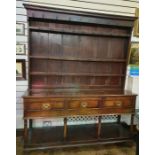 18th century oak dresser with ogee moulded pediment, three shelves with iron cup hooks, on base of