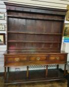 18th century oak dresser with ogee moulded pediment, three shelves with iron cup hooks, on base of