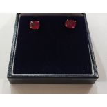 Pair of white metal heat-treated ruby stud earrings, each set oval cut stone