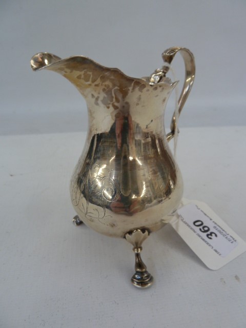 George III silver cream jug, baluster-shaped with scroll handle and raised on three hoof feet,