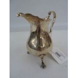 George III silver cream jug, baluster-shaped with scroll handle and raised on three hoof feet,