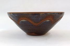 Studio pottery terracotta bowl with purple and brown glazes, whirl decoration and incised border