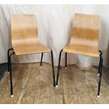 Two plywood shaped dining chairs on four metal legs, the plywood sheet bent to form the seat and