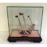 Eastern white metal model of a Dhow, on stand, in glass case