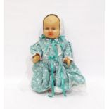 Rubber baby doll wearing green and white floral dress, pantaloons and bonnet, 31cm