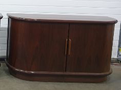 Two Eastern hardwood sideboards of elongated D form, tambour fronted roller doors enclosing