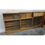 Light oak modular lounge suite comprising a corner unit, assorted glass-fronted shelving units, a