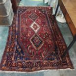 Red ground Persian rug with three diamond-shaped interlinked medallions, foliate decorated field,