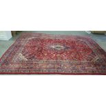 Red ground rug with stepped central foliate decorated medallion, the field with allover foliate