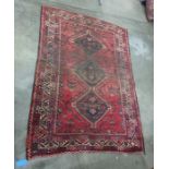 Red ground rug with three black ground interlinking central medallions, on a stepped border, 265cm x