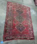 Red ground rug with three black ground interlinking central medallions, on a stepped border, 265cm x