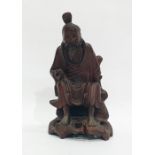 Chinese hardwood sculpture of an Immortal, modelled seated on pierced rockwork holding a bag, 18cm