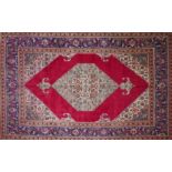 A North West Persian Tabriz carpet, central diamond medallion on a rouge field, guarded by a