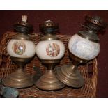 A set of three ceramic and brass oil lamps, together with extra glass chimneys and various copper