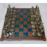 A 20th century Greek chess set, with brass pieces on a copper clad board