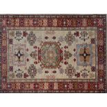 A Kazak rug with three geometric motifs, on a beige ground, contained by geometric border, 146 x